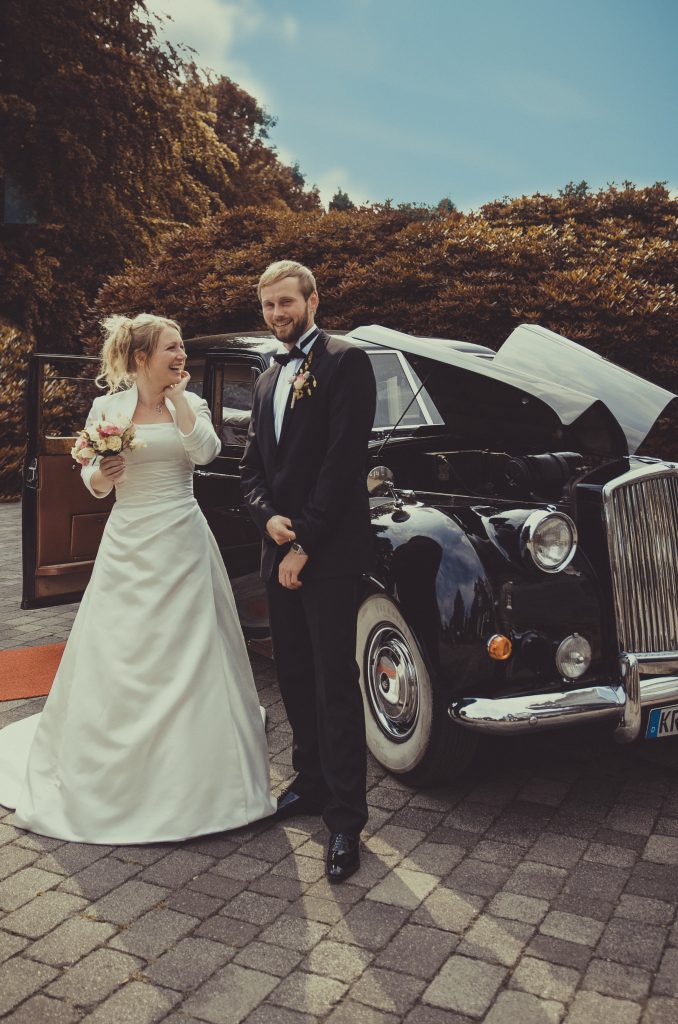 ein Hochzeitspaar steht vor dem auto
