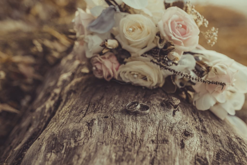 Hochzeitsblumenstrauß mit Ringen auf Holz